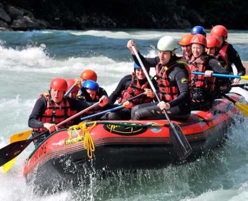 Beidhändige Führung: Gruppe (Team) im Schlauchboot beim Rafting.